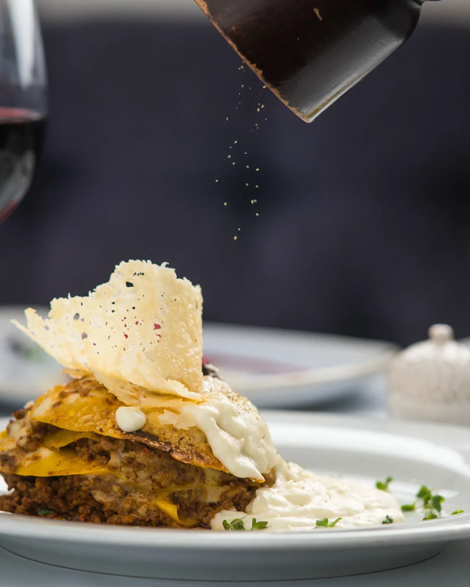 Dressage soigné d'un plat lors d'une soirée à thème, verre de vin en arrière-plan